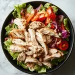 Grilled chicken served over fresh vegetables in a healthy chicken salad bowl.